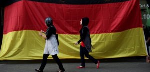 BERLIN - JULY 07: Two young Muslim women walk by a pub draped in a German flag in the Arab and Turkish-heavy neighborhood of Neukoelln during the FIFA 2010 World Cup match between Germany and Spain on July 7, 2010 in Berlin, Germany. Many immigrants in Germany identify strongly with the German national team, in part because many of the team's members have African, Arab, Turkish or East European roots. (Photo by Sean Gallup/Getty Images)